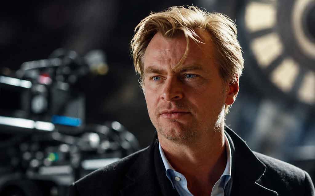 Christopher Nolan promoting The Odyssey with cinematic film reels and practical filmmaking elements representing authentic storytelling over AI-generated content